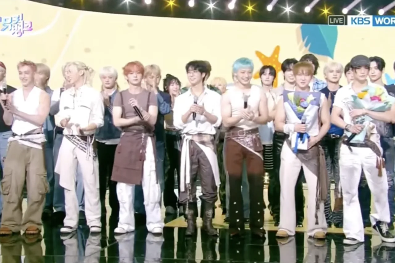 Membros do Stray Kids em roupas esportivas, realizando treinos de alta intensidade na academia, com halteres e esteira ao fundo