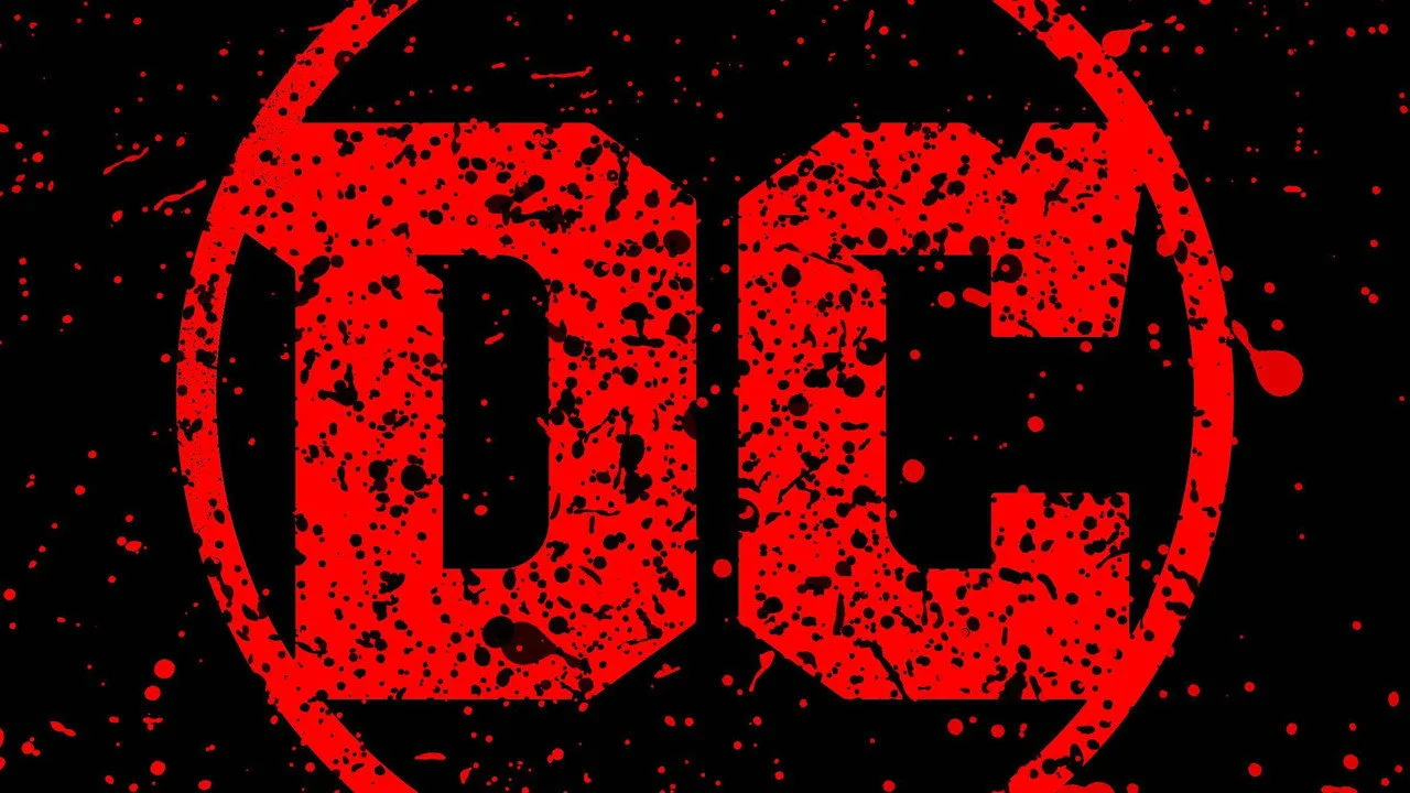 Homem usando camiseta com logo DC, segurando halteres ao lado de quadrinhos espalhados sobre o chão