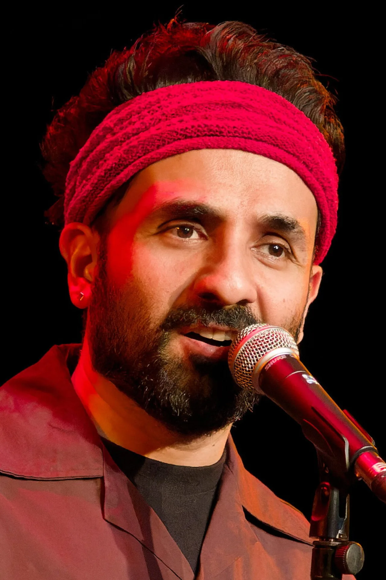 Vir Das em roupa de treino, segurando um script ao lado de um haltere no estúdio