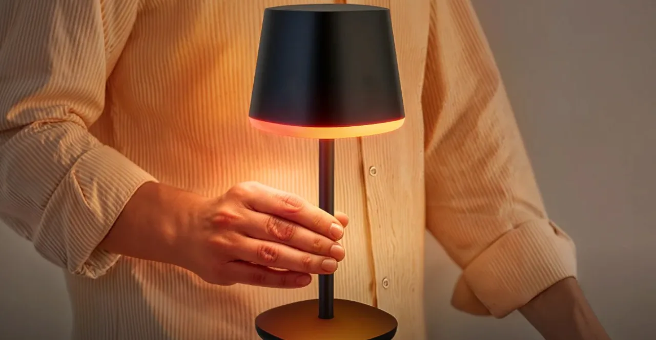 Mulher medita em tapete de yoga sob a luz âmbar de uma luminária portátil sobre a mesa de cabeceira