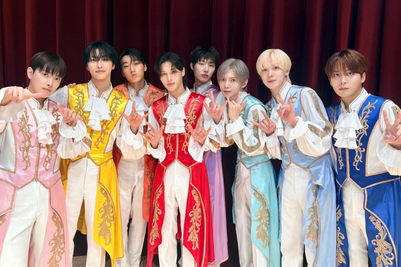 Membros do ATEEZ cantam “BAD” no palco iluminado do Inkigayo, com o logo do programa ao fundo