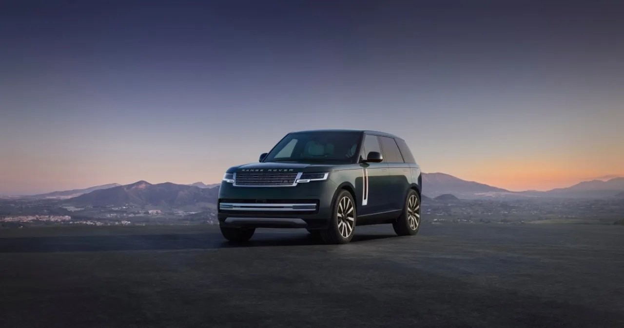 Modelo em roupas de ginástica faz alongamento ao lado da Range Rover EV, segurando garrafa de água e smartwatch