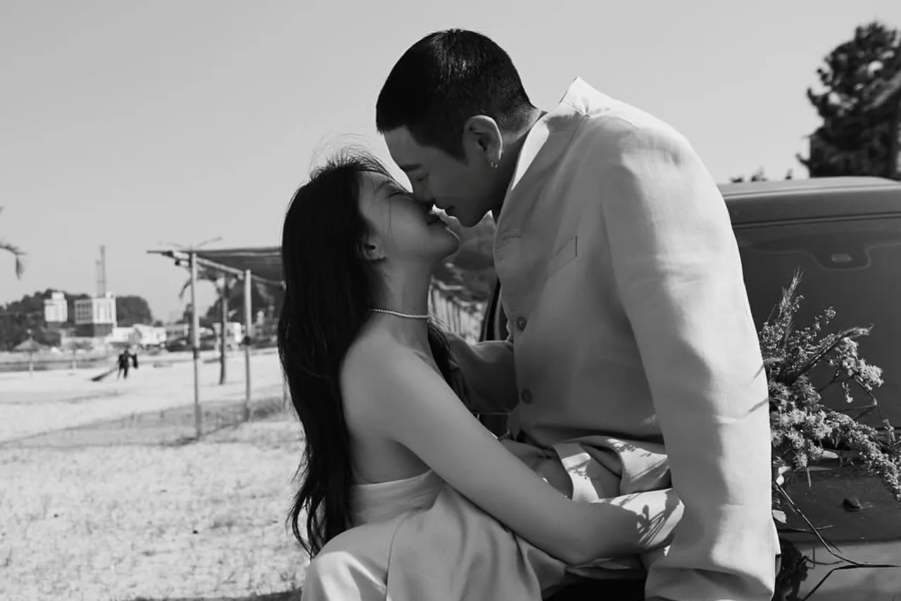 Won Hyun Jun e Lee Su Jin aparecem de terno e vestido branco, sorrindo juntos em cenário de casamento