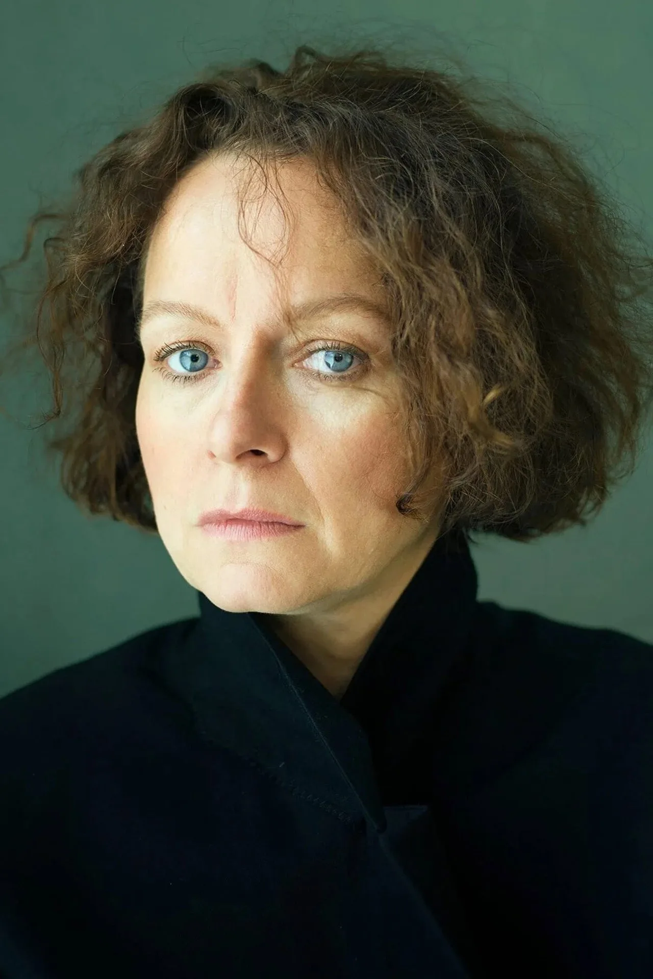 Samantha Morton vestindo roupa esportiva, fazendo agachamento com halteres em um set de filmagem