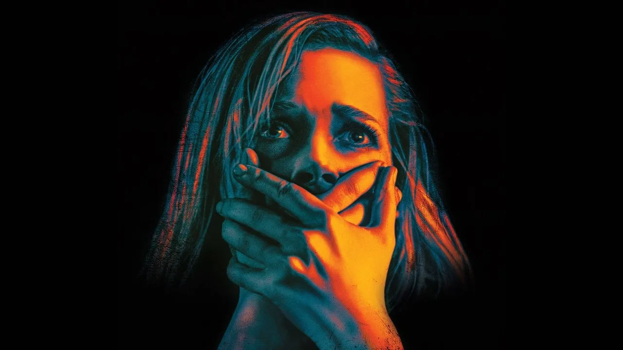 Homem usando máscara de oxigênio, braços cruzados, ao lado de pôsteres de Don’t Breathe e Don’t Breathe 2