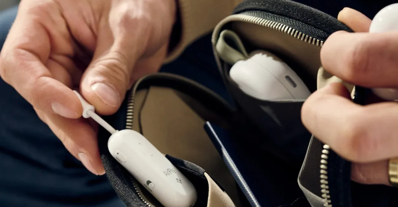 Pessoa usando fones de ouvido sem fio conectados ao AirFly Pro 2 em uma poltrona de avião com tablet à frente