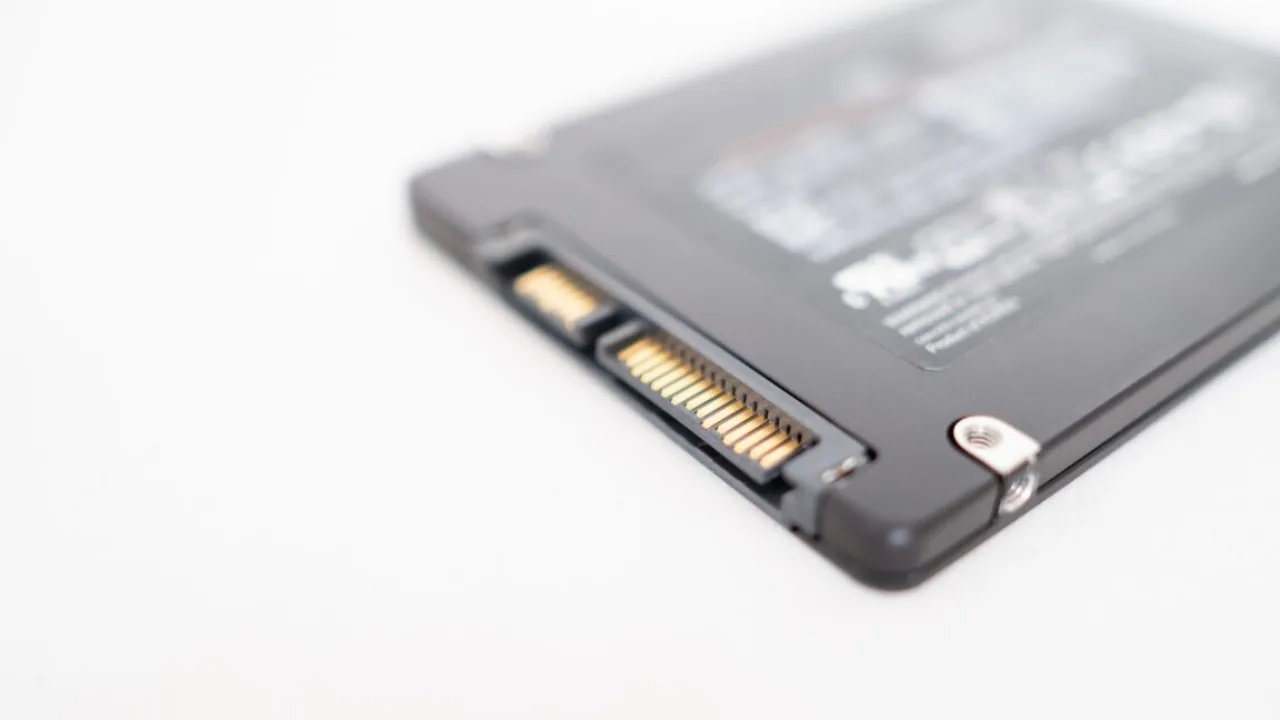 Close-up de um SSD de alta performance conectado a um computador, com luzes neon azuladas e cabos de dados expostos