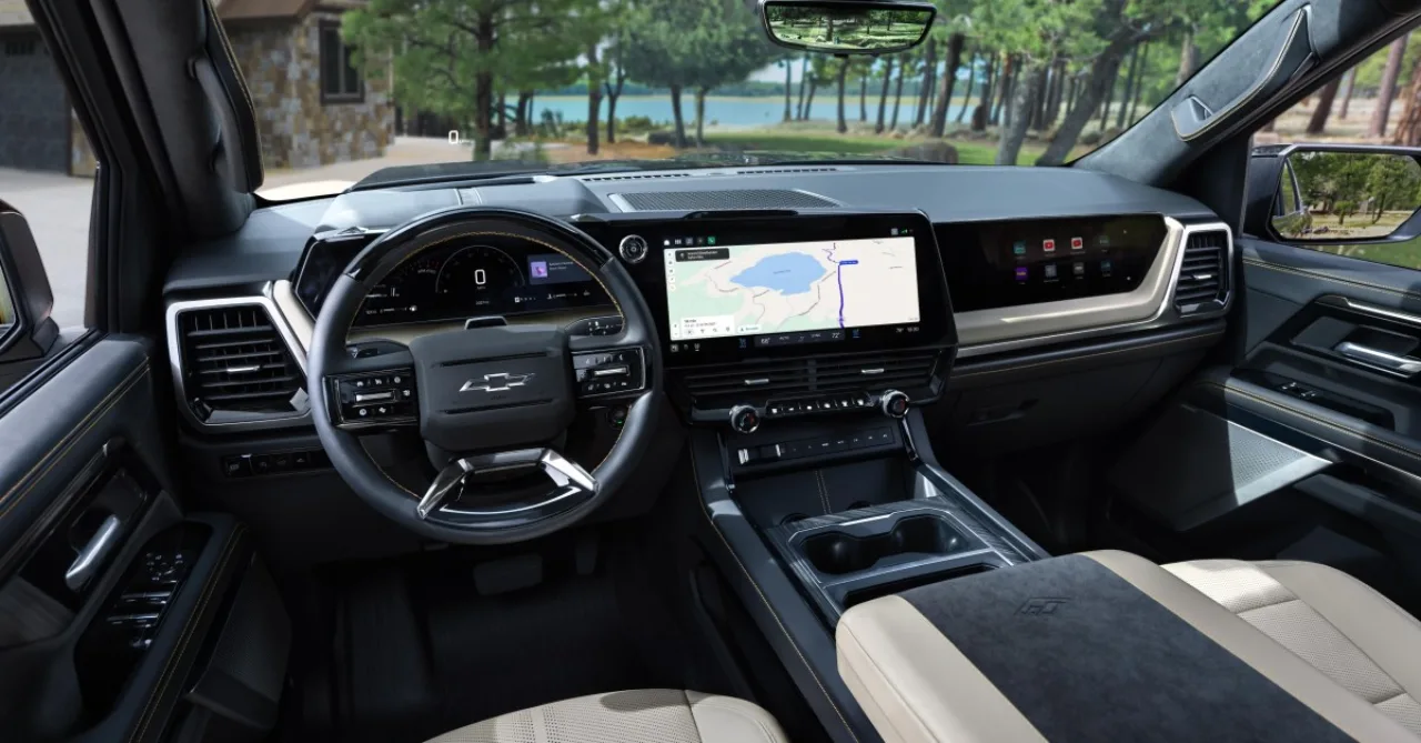 Tela de infotainment de um caminhonete GM exibindo CarPlay e Android Auto em picture‑in‑picture, com logo da GM ao fundo