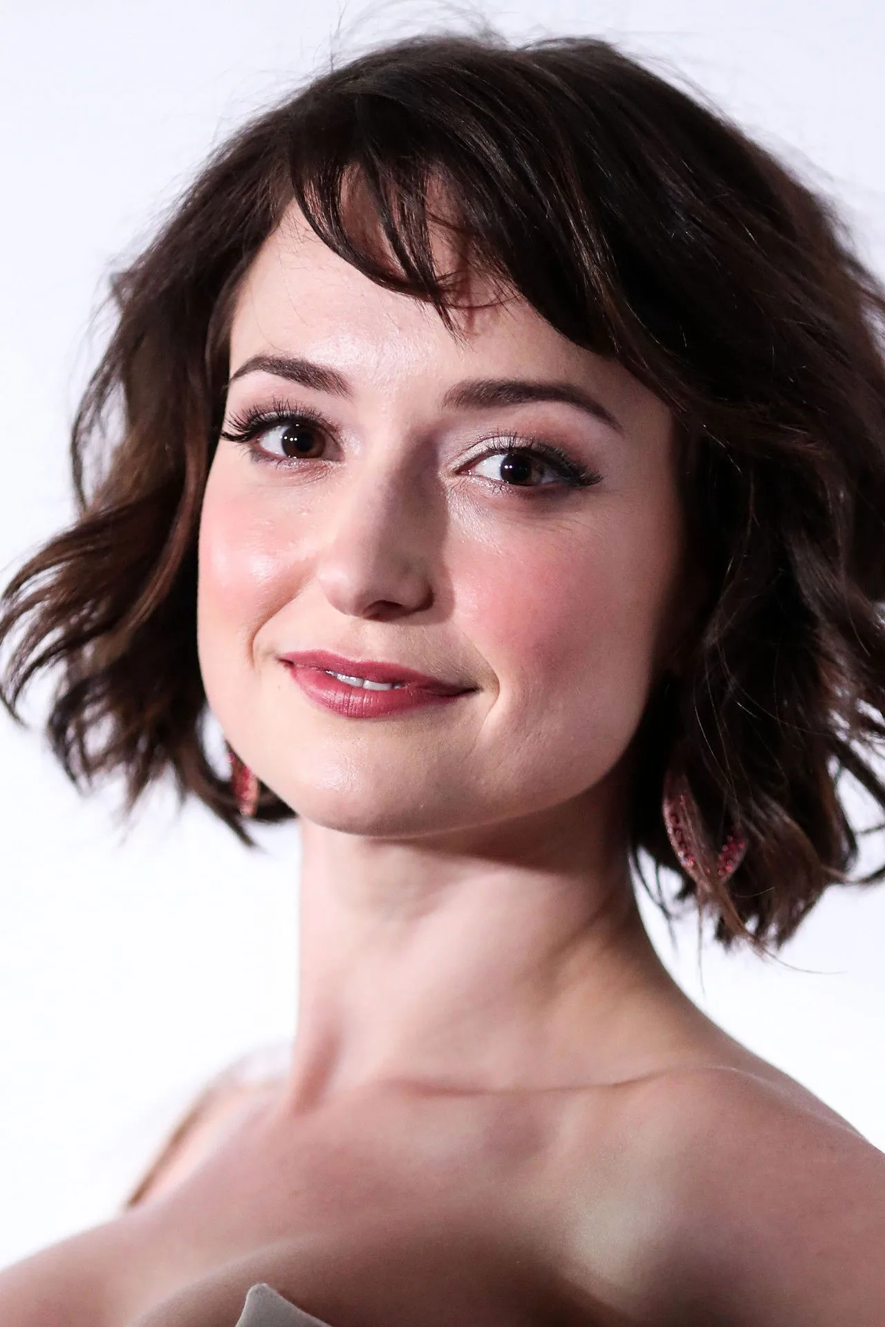 Milana Vayntrub, vestida como Squirrel Girl, faz alongamento com halteres ao lado de um tapete de yoga