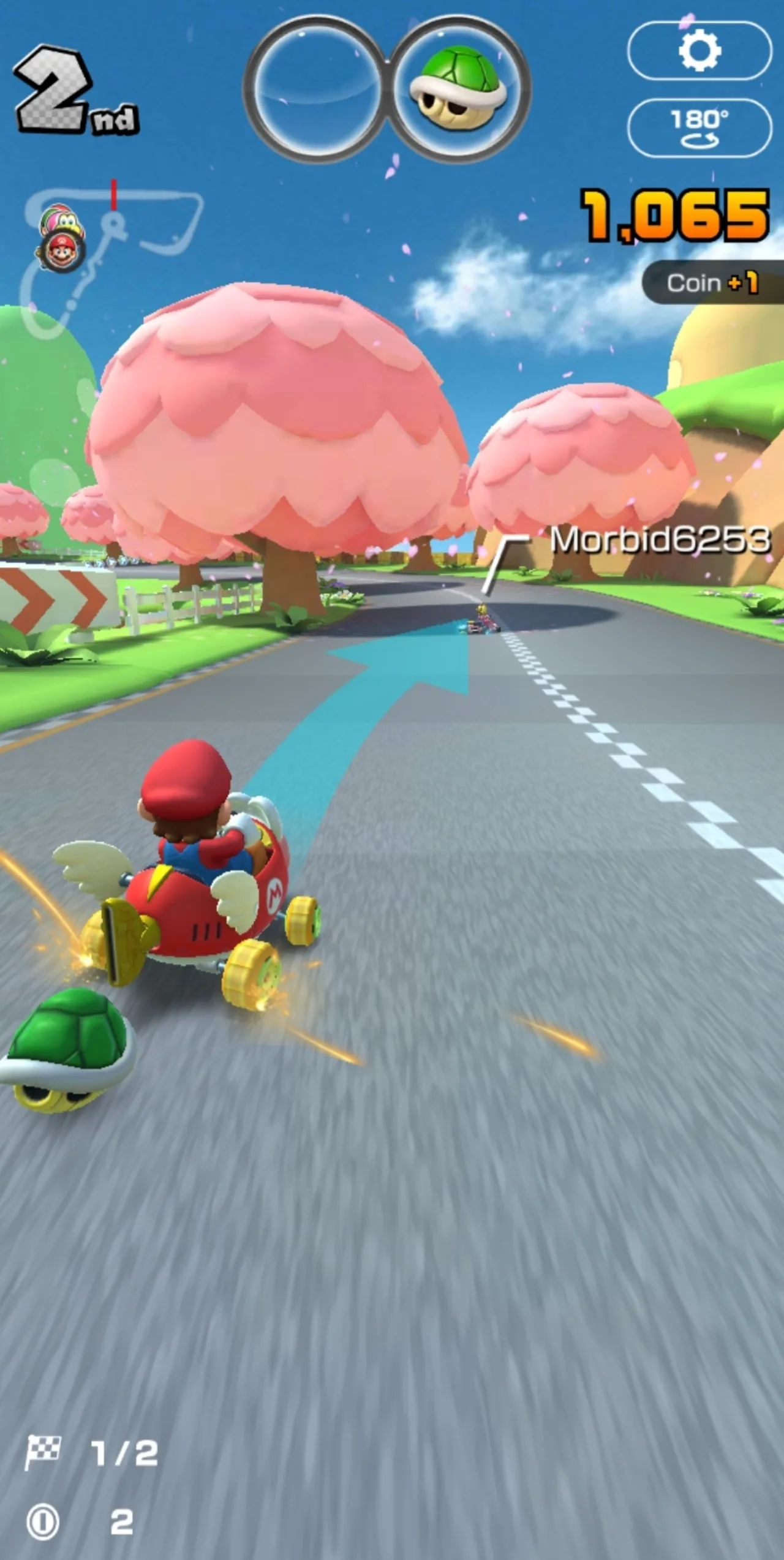 Jogador segurando smartphone com Mario Kart Tour aberto, ao lado de tênis de corrida e garrafa de água
