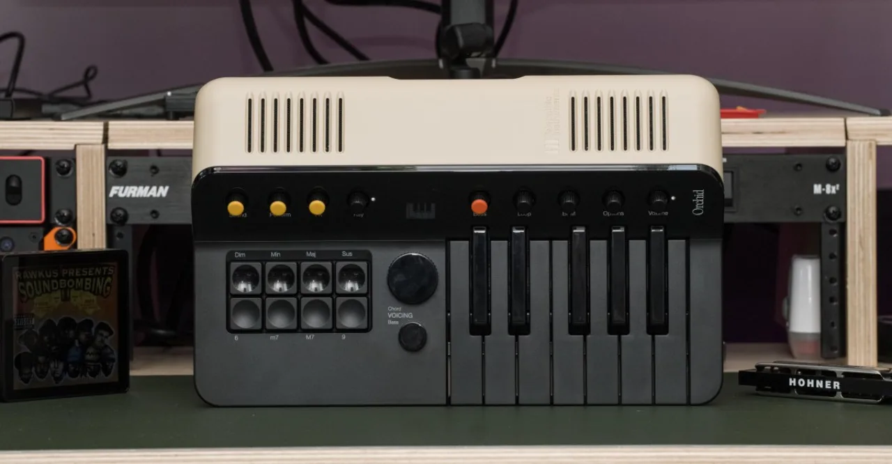 Um teclado compacto Magnus Chord Organ aberto, com luzes LED acesas e cabos USB conectados a um laptop