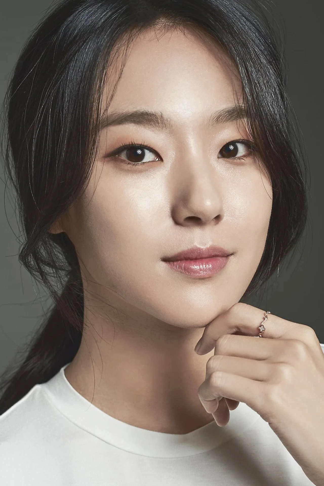 Lee Min Jung meditando em estúdio claro, com tapete de ioga e halteres leves ao fundo