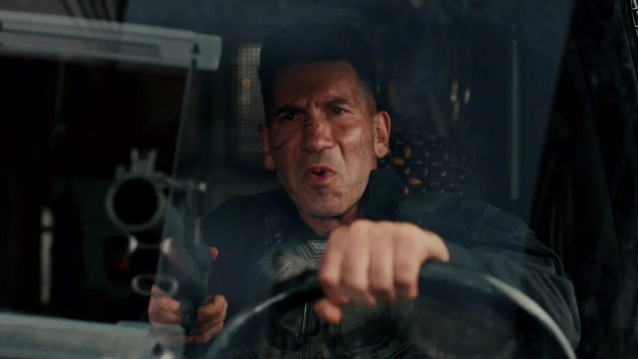 Homem musculoso em camiseta preta faz flexão ao lado de uma pilha de edições de “The Punisher”, incluindo “Brand New Day”