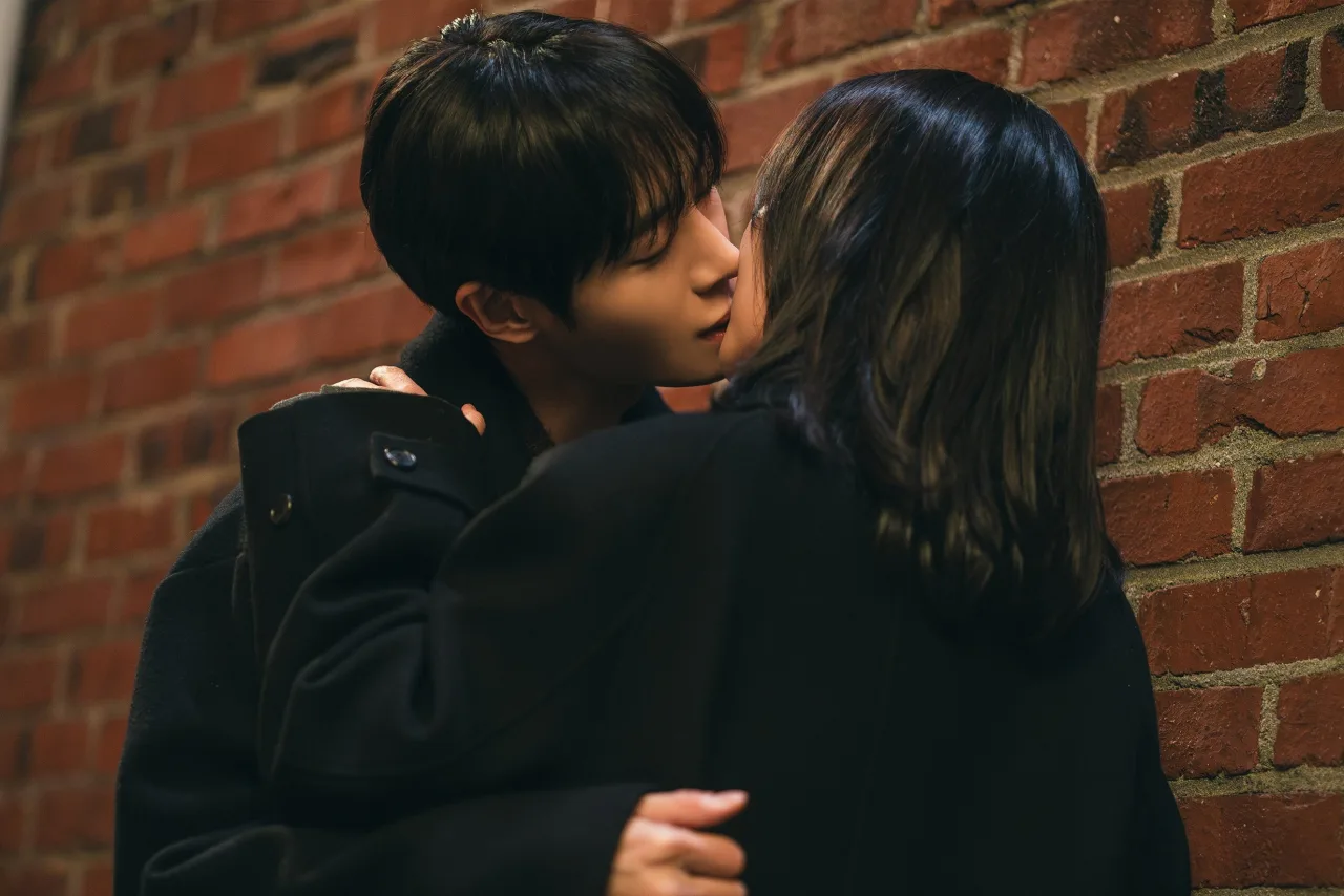 Kim So Hyun e Choo Young Woo se beijam num beco escuro, ele usando um chapéu excêntrico
