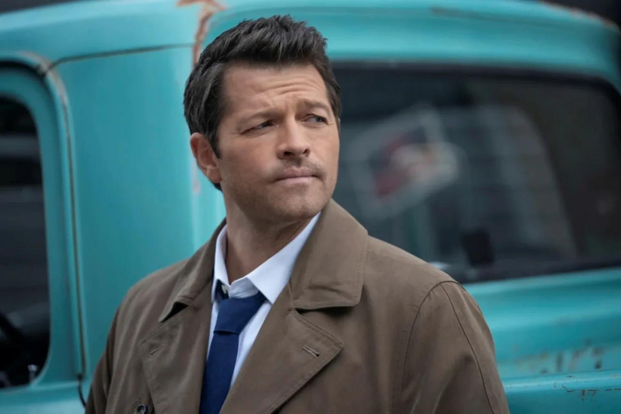 Castiel, o anjo de Supernatural, aparece em close com suas asas brancas e o logotipo da série ao fundo
