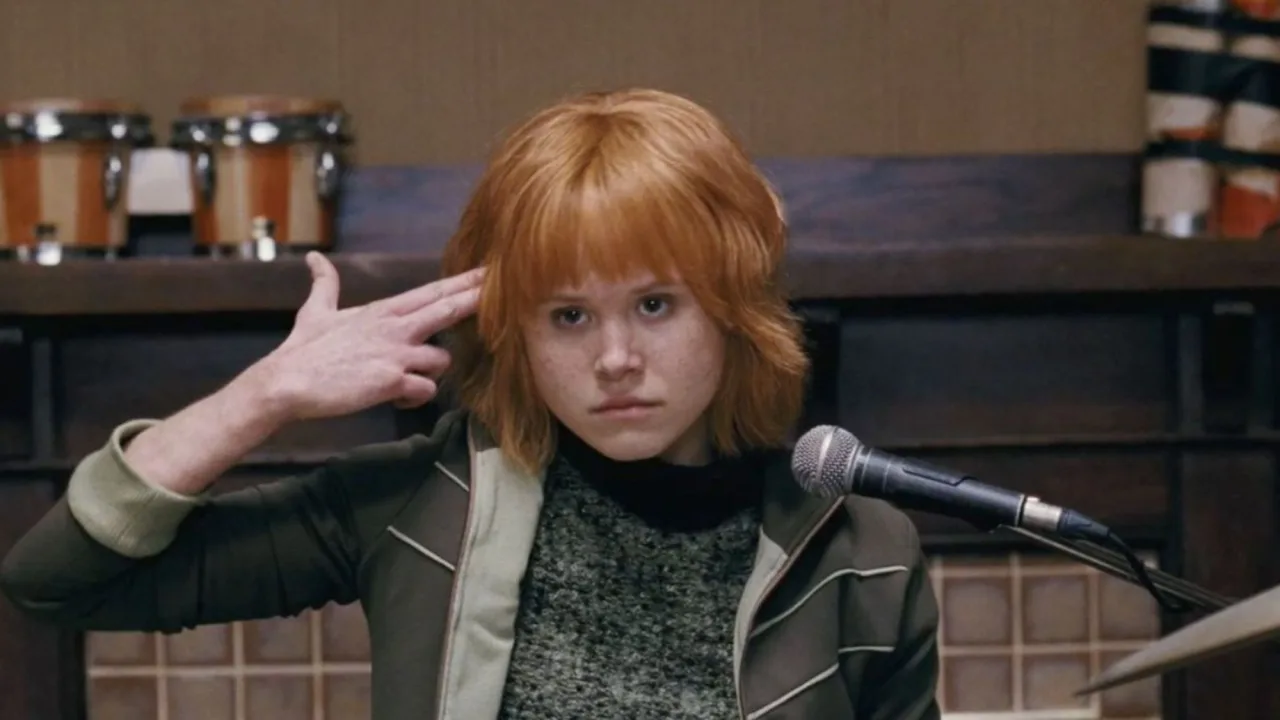 Jovem fazendo flexão sobre um tapete, com pôster de Scott Pilgrim ao fundo e garrafa de água ao lado