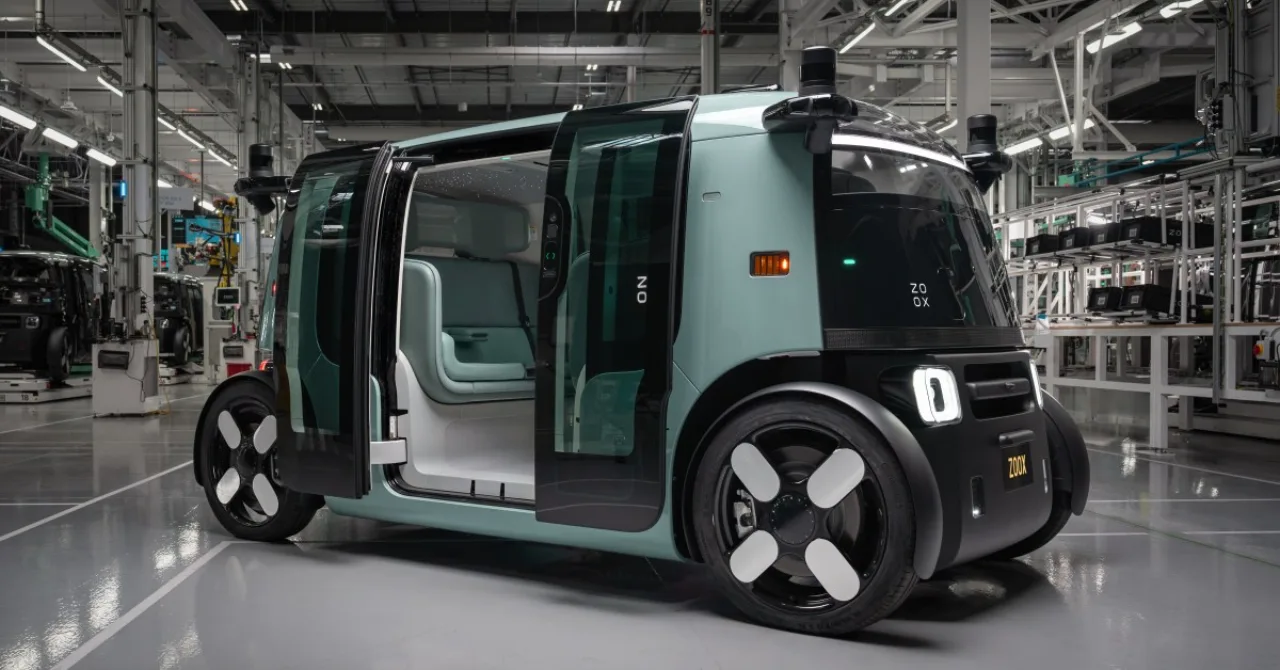 Interior do robotaxi da Zoox com assentos giratórios e passageiro praticando alongamento