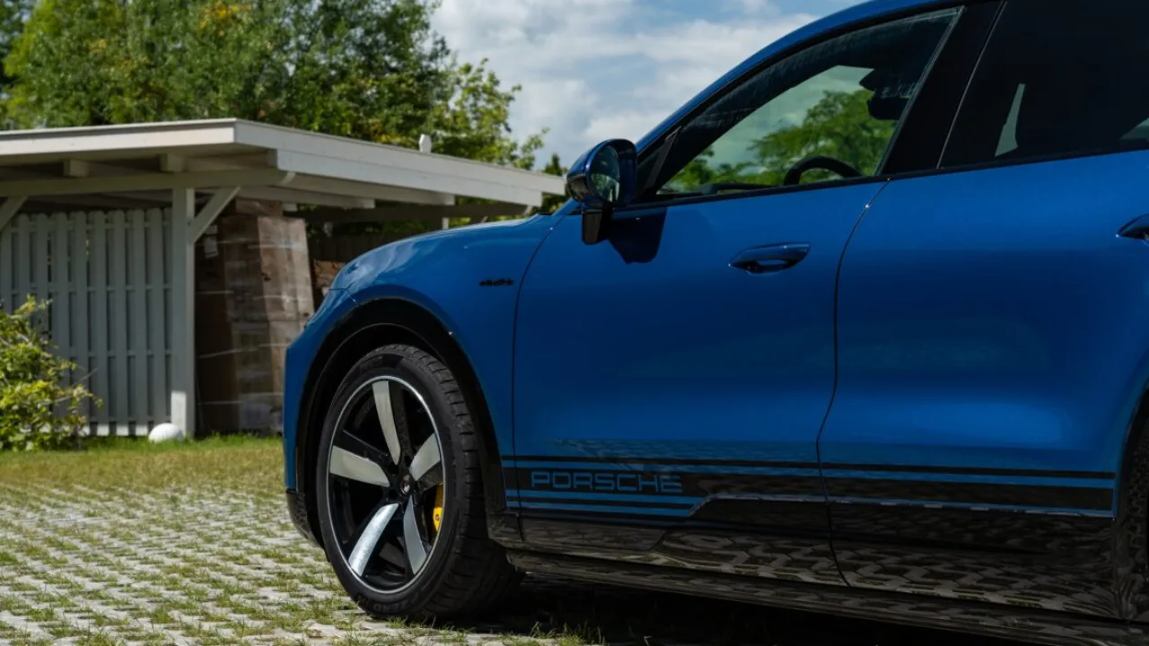 Pessoa atlética em roupa esportiva ajustando um smartwatch moderno ao lado de um Porsche Cayenne estacionado