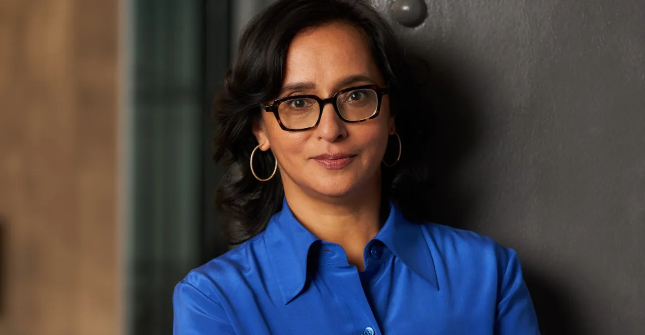 Kakul Srivastava em entrevista, ao lado de tela exibindo ícones de e‑mail e símbolos de IA, com logo da Splice ao fundo