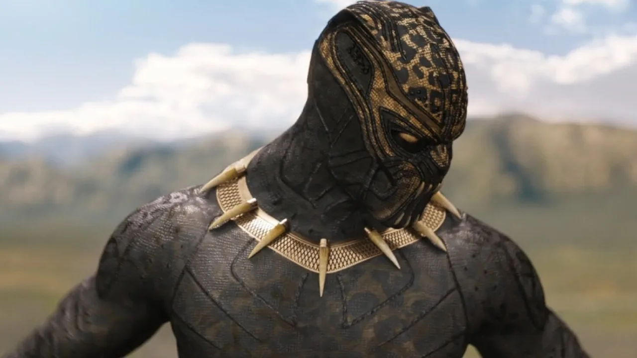 Traje dourado de Killmonger exposto em pedestal, detalhes do couro metálico reluzente e máscara icônica