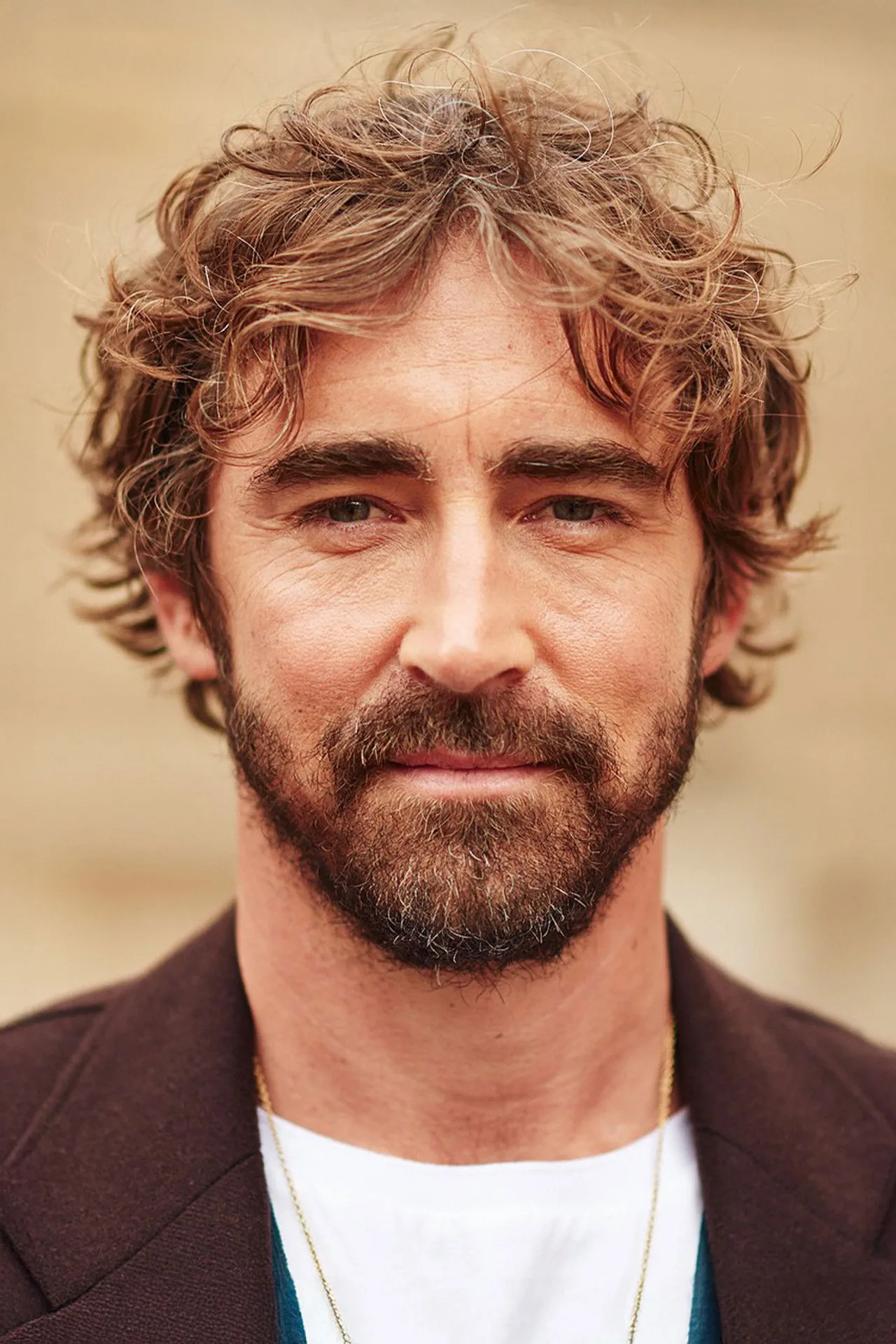 Lee Pace em traje de treino, segurando halteres, suor escorrendo, fundo de academia com espelhos e pesos