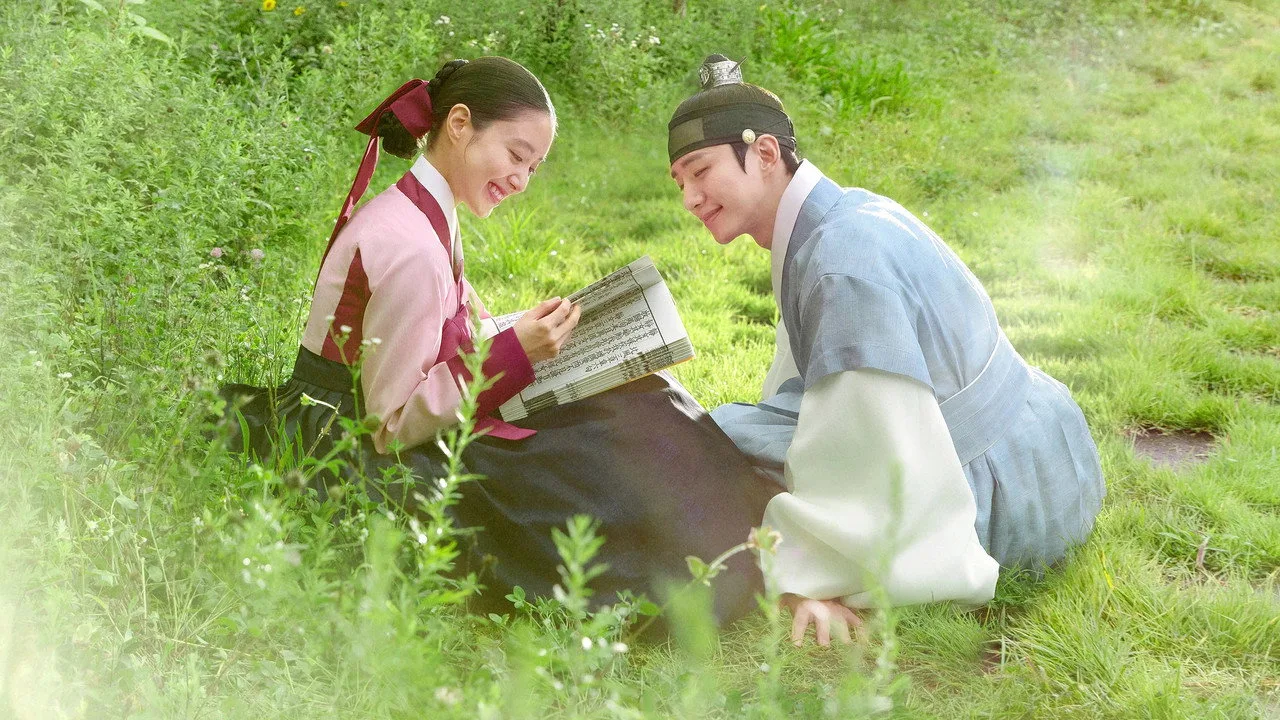 Kang Hoon em roupa de treino, segurando halteres, ao fundo pôsteres de dramas da npio Entertainment
