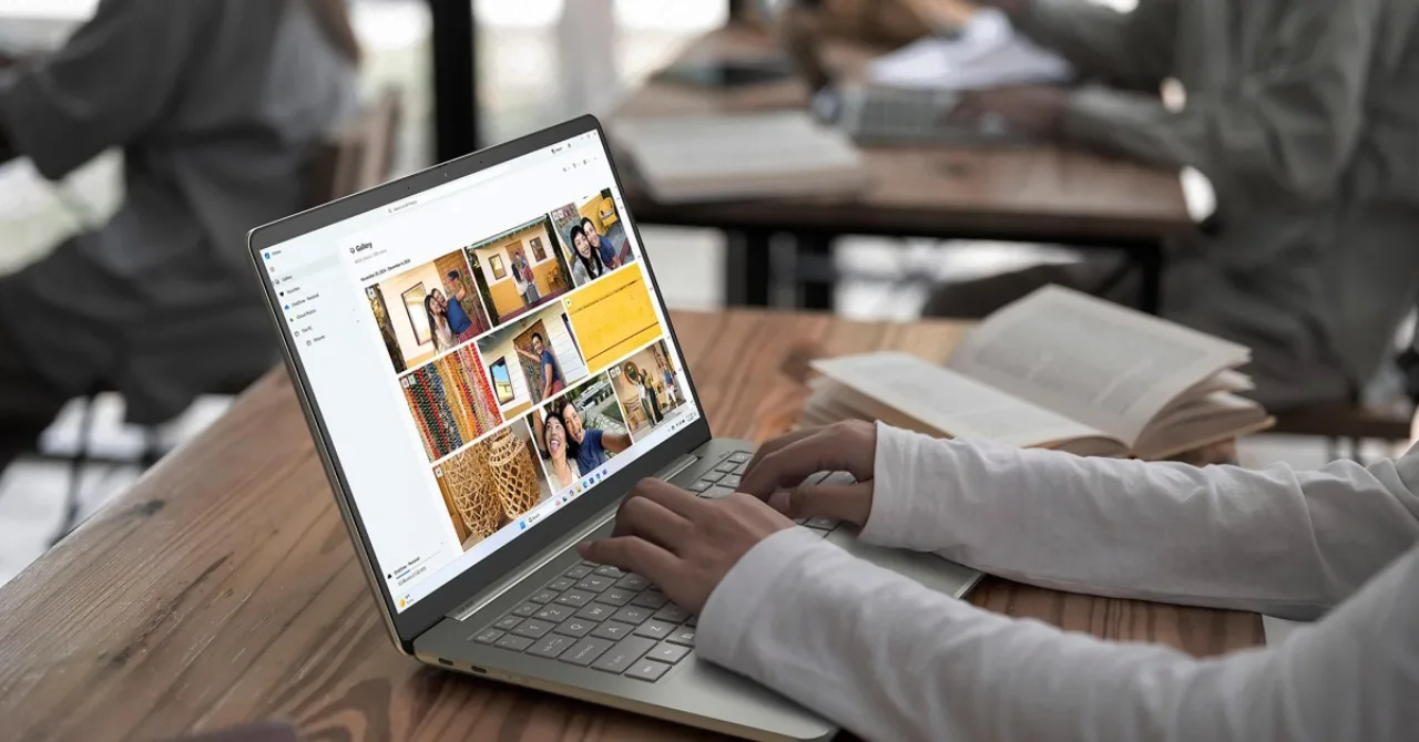 Notebook ultrafino aberto sobre uma mesa minimalista ao lado de um café e um caderno de anotações em escritório
