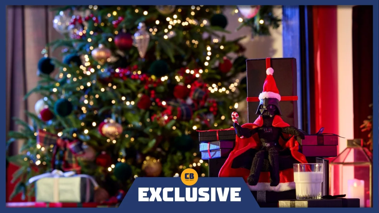 Pelúcia do Darth Vader vestida de vermelho ao lado de um trenó natalino e luzes festivas da Disney Store