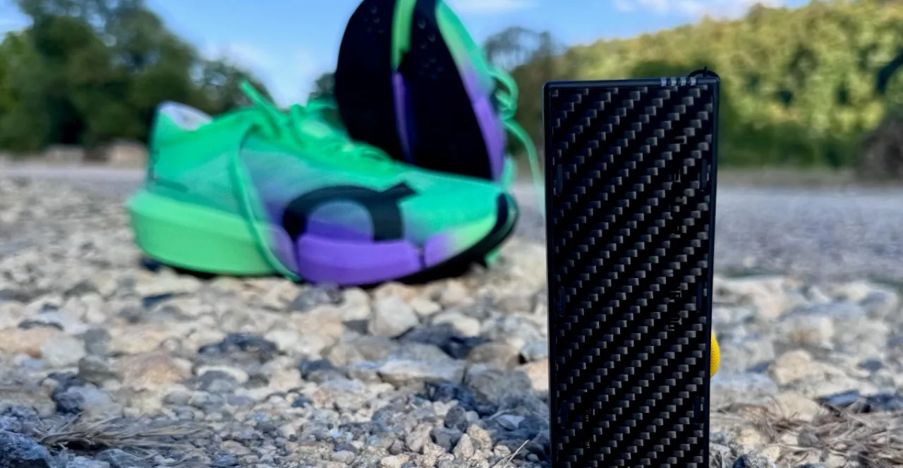 Um(a) trekker em trilha, usando mochila leve, segurando o Nitecore NB10000 enquanto recarrega um smartwatch