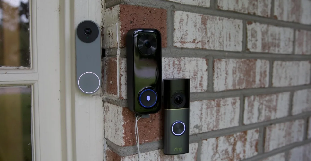 Câmera Apple Home AI sobre uma mesa ao lado dos dispositivos Ring e Nest, com seus logotipos ao fundo