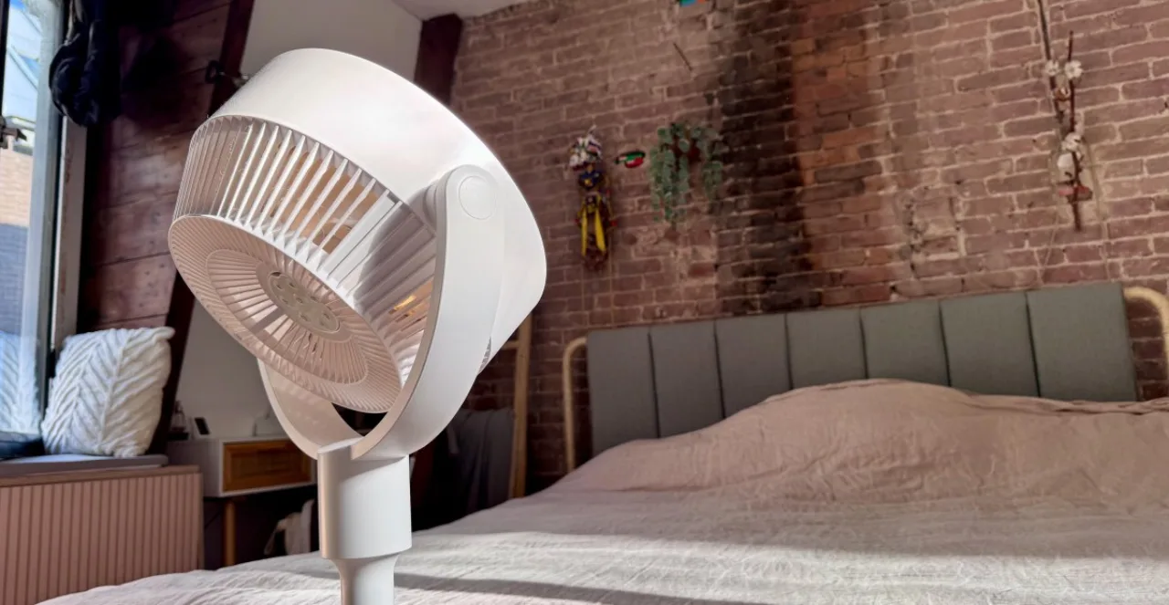 Homem em roupa de academia suando, com o ventilador de pé SwitchBot ao lado do tapete de yoga