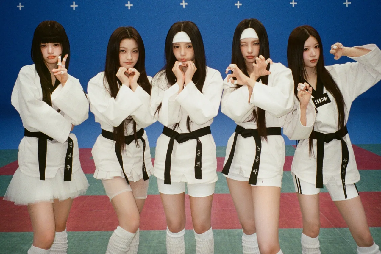 Membros da ILLIT posam em cenário neon do clipe 'It's Me', com logo da banda e contagem de 200 milhões de visualizações