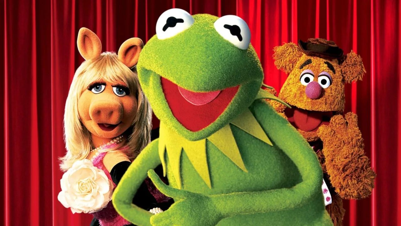 Pessoa fazendo prancha ao lado da estátua de Kermit, com halteres e toalha de ginásio ao fundo