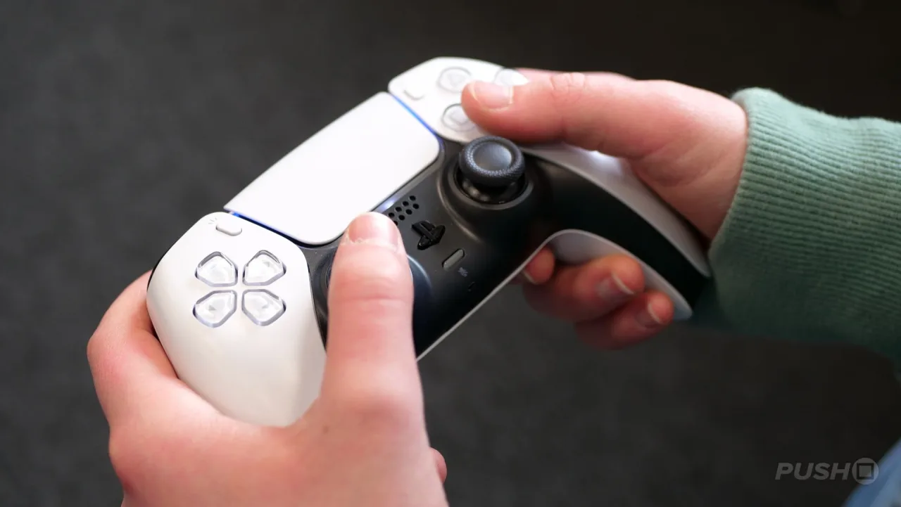 Jovem gamer sentado, usando fone, faz alongamento de braços ao lado de console e tela azul