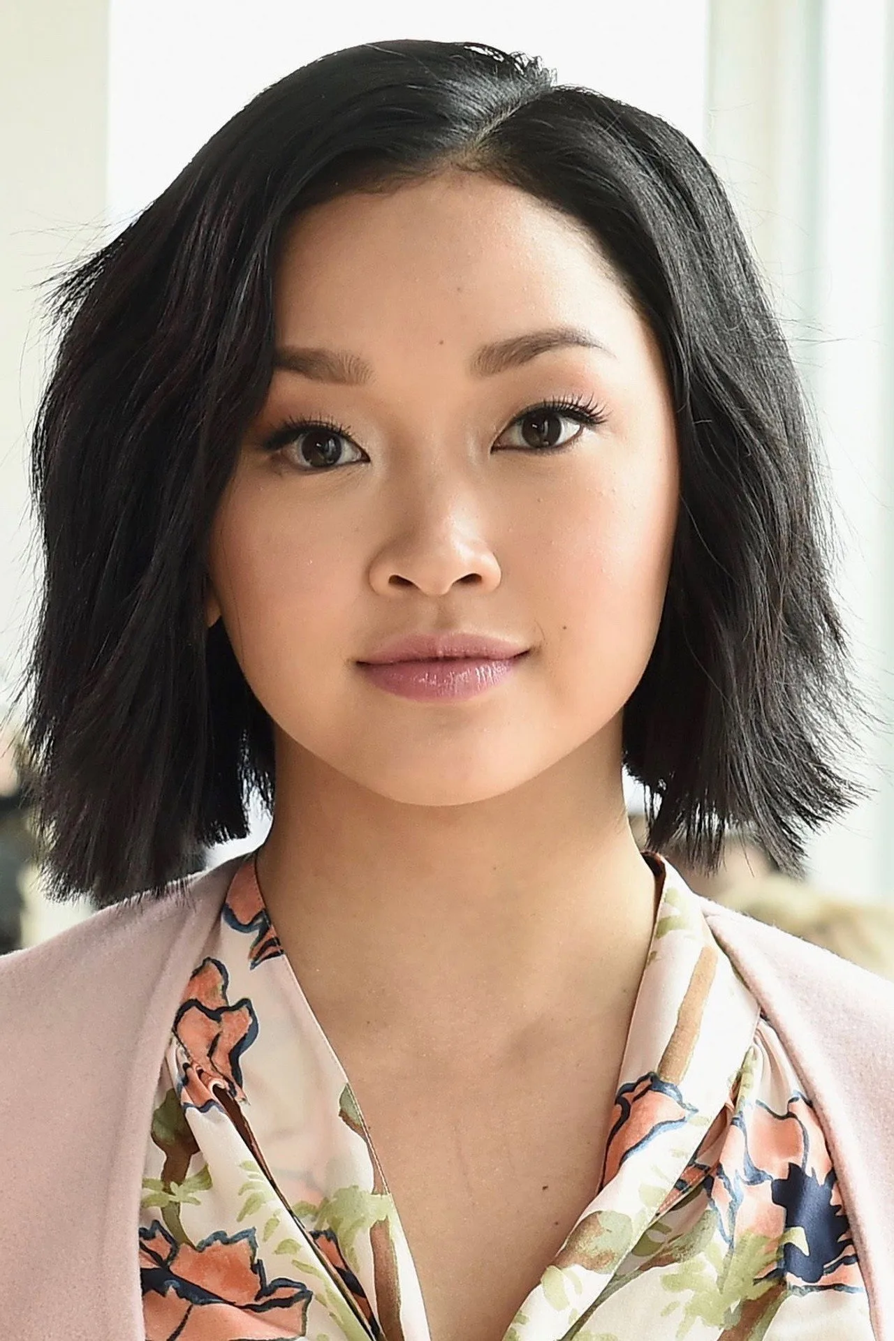 Lana Condor em leggings pretas, fazendo agachamento com halteres, ao lado de pôsteres dos X‑Men na academia