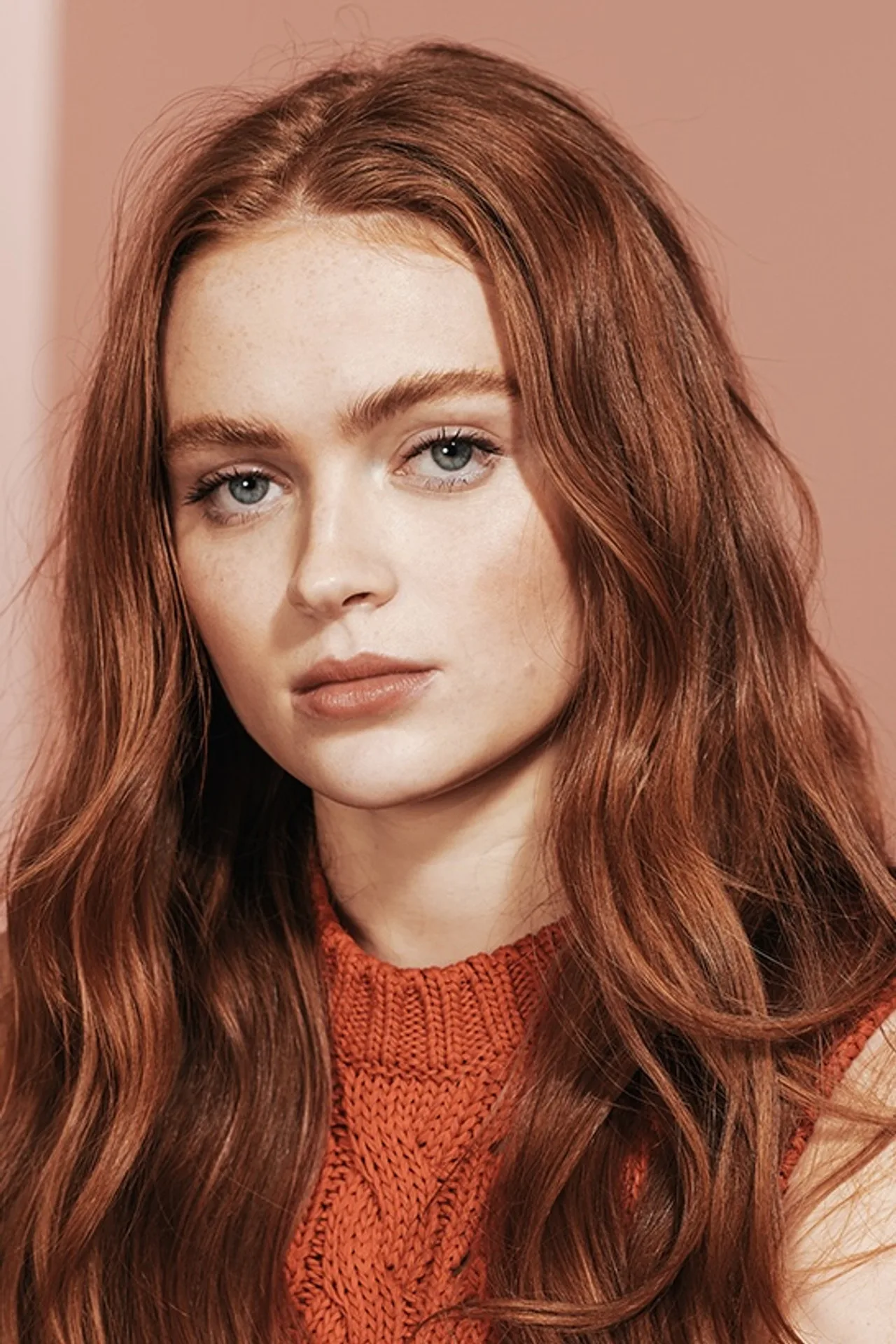 Sadie Sink vestindo roupa esportiva, fazendo agachamento com halteres em academia iluminada