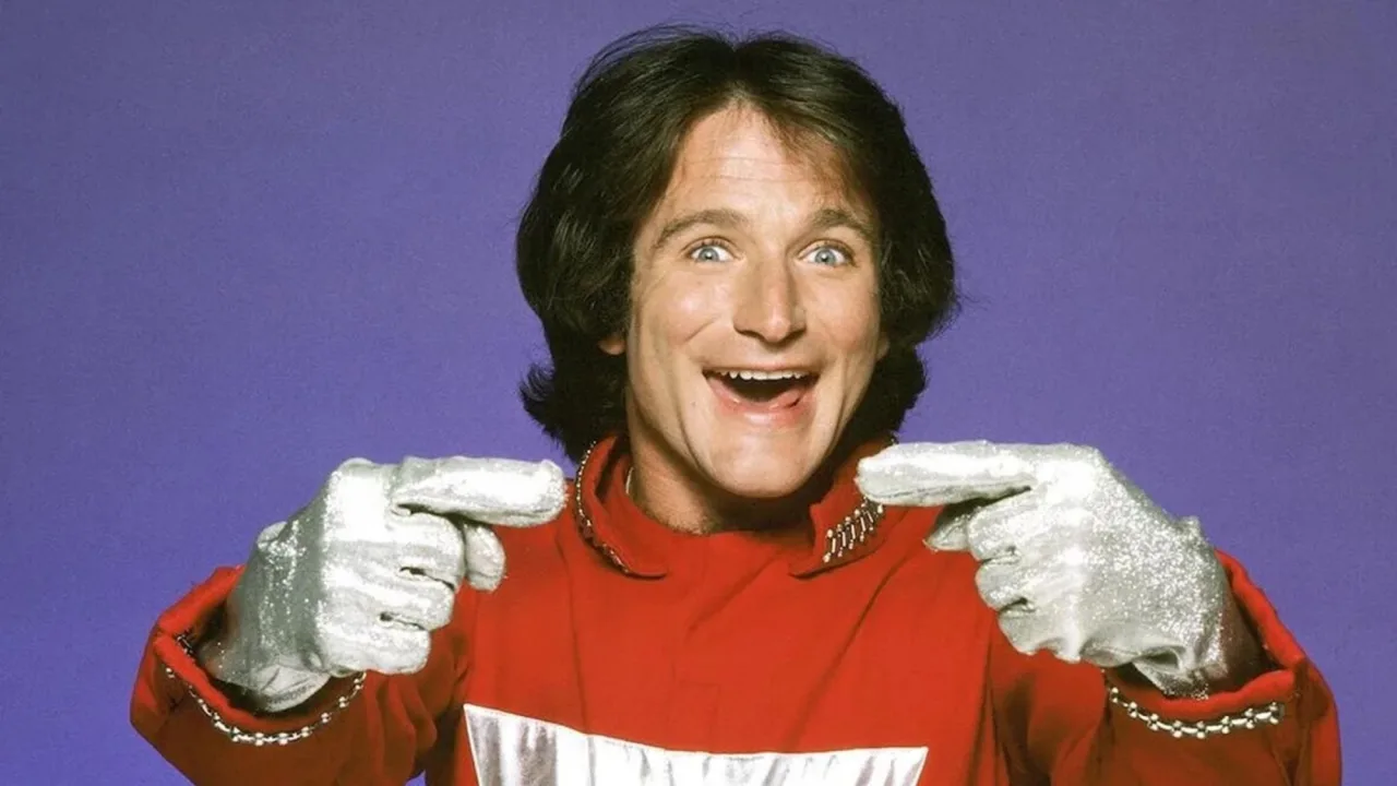 Robin Williams como Mork, em seu traje azul, ao lado dos logotipos de Happy Days, Mork & Mindy, The Cosby Show e Family Ties