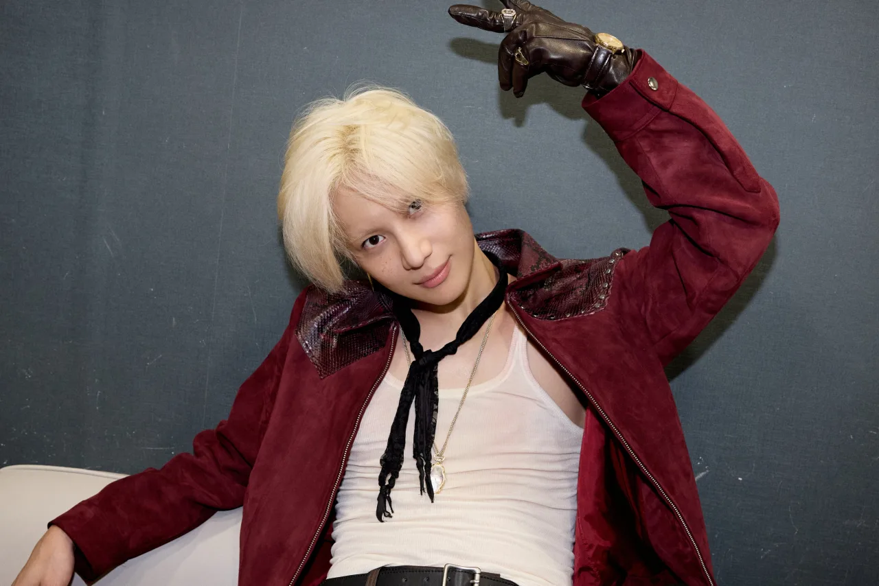 Taemin, em traje futurista, segura o troféu no palco iluminado do Music Core, ao fundo o logo do programa