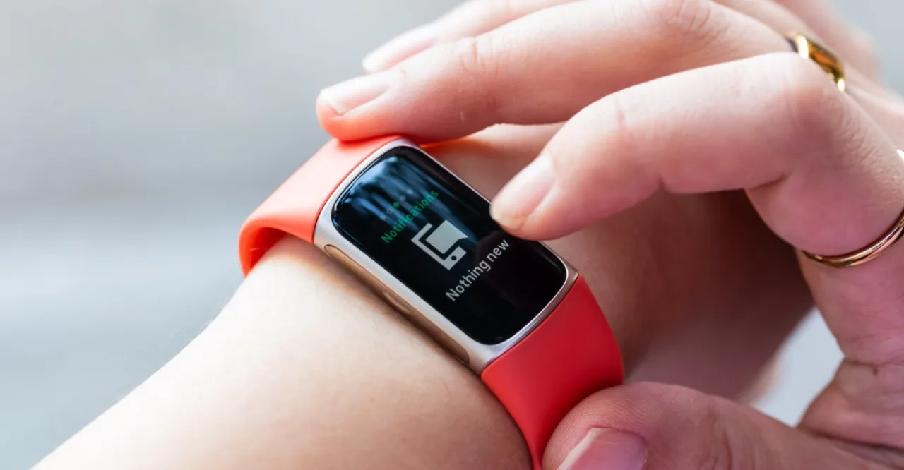 Pulseira fitness azul com mostrador digital, fita de silicone, monitor de batimentos e um tablet infantil ao lado