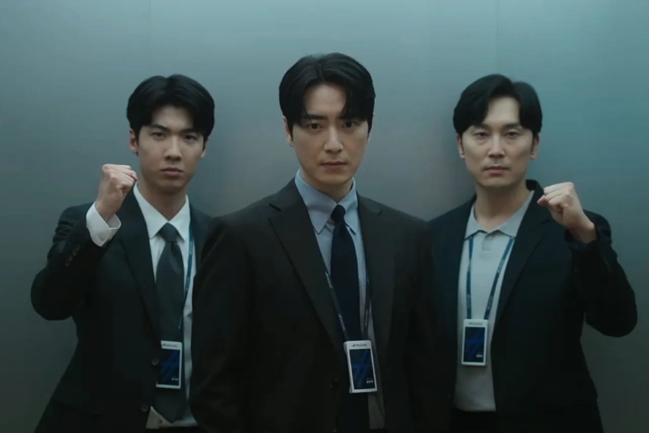 Gong Eun Tae e Yang Joon Ho de pé ao lado de uma pilha de notas e um letreiro de jackpot, trocando olhares tensos