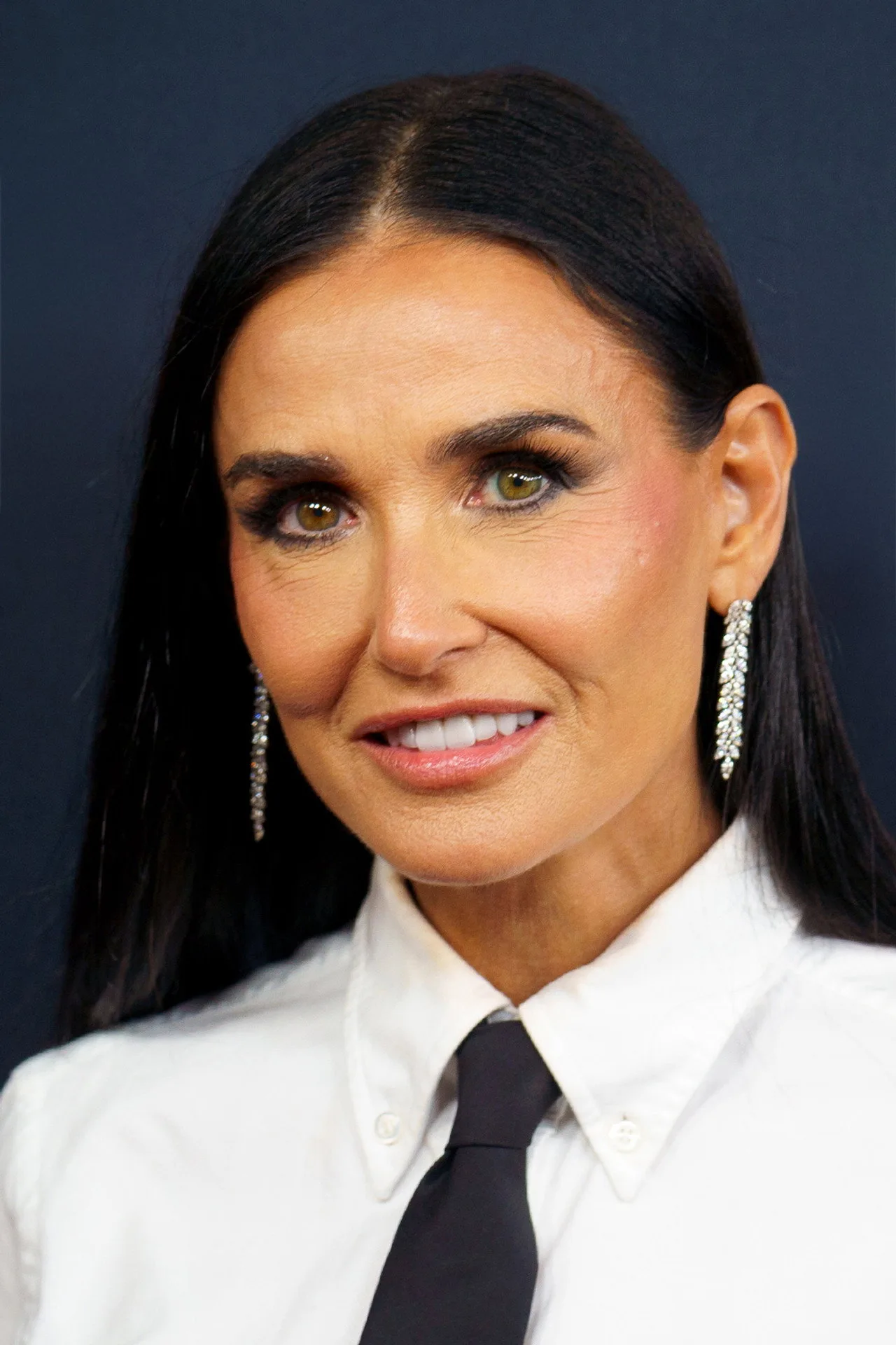 Demi Moore segura um suco verde e um haltere, destacando sua forma física em um terraço ensolarado de Cannes