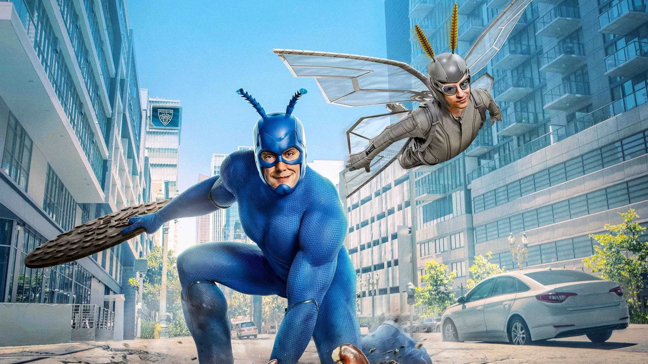 Ator musculoso vestido de azul como The Tick levanta halteres, com logo da Netflix ao fundo