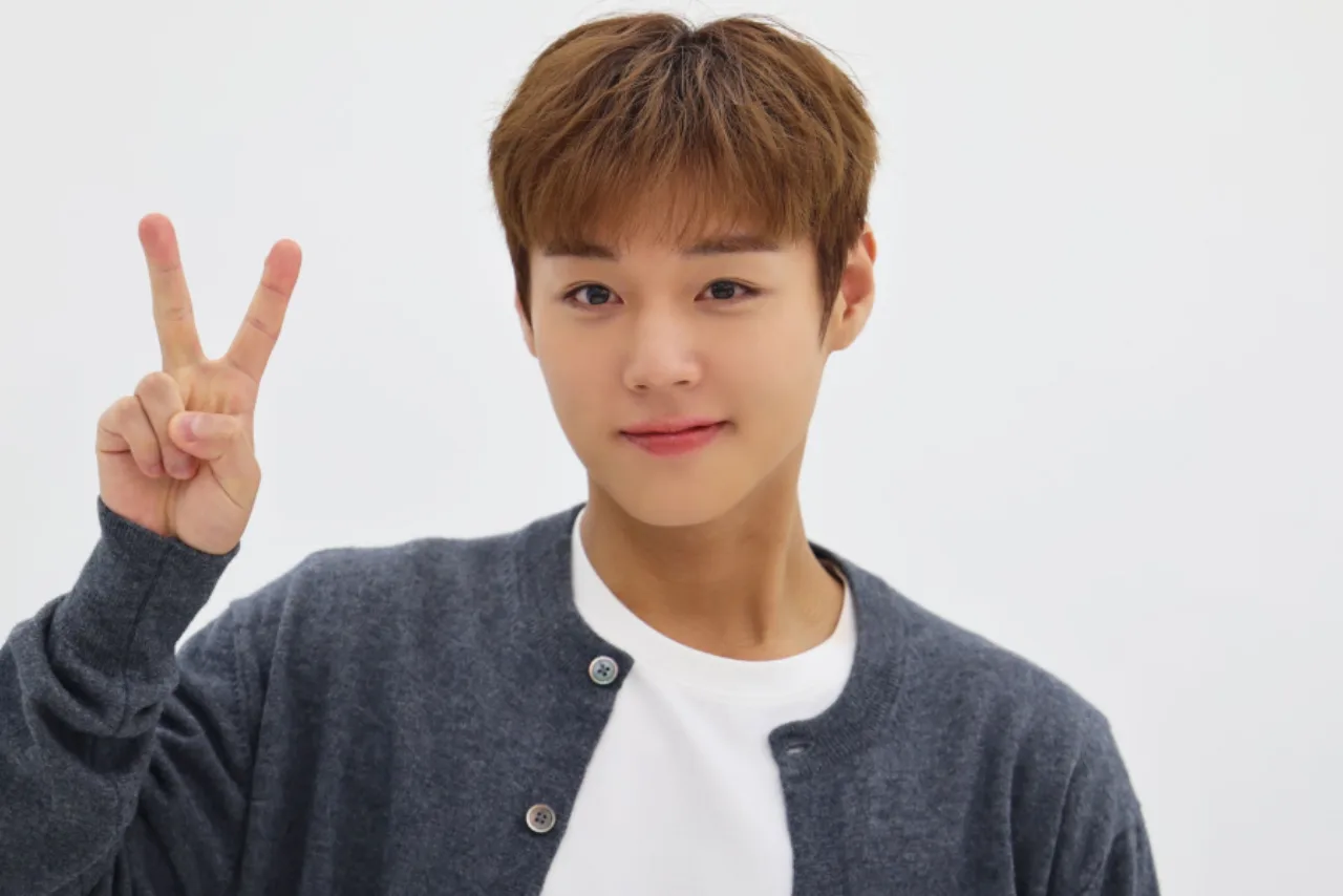 Jovem malhando na academia, usando camiseta de Park Ji Hoon, segurando o Light Stick V2 iluminado ao lado de halteres