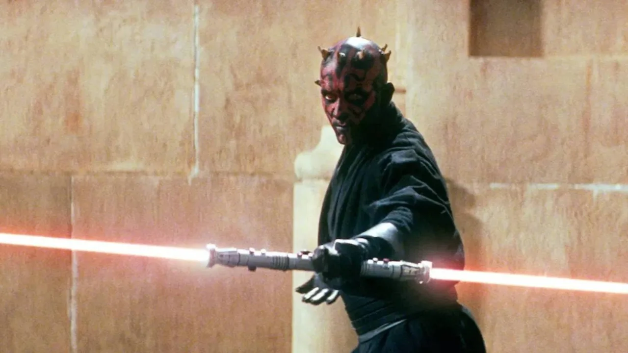 Sable duplo vermelho de Darth Maul, com lâminas iluminadas, sobre um pedestal preto, ao lado do logo da Heritage Auctions