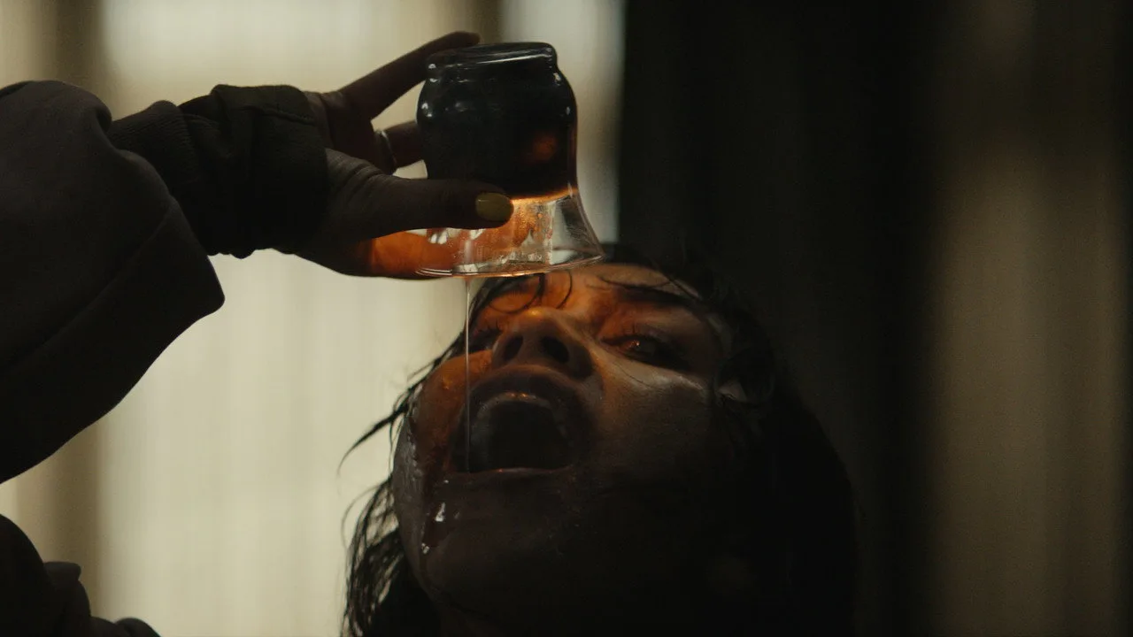 Jovem em roupa de treino segurando barra, ao fundo pôster de Evil Dead Burn com sangue estilizado