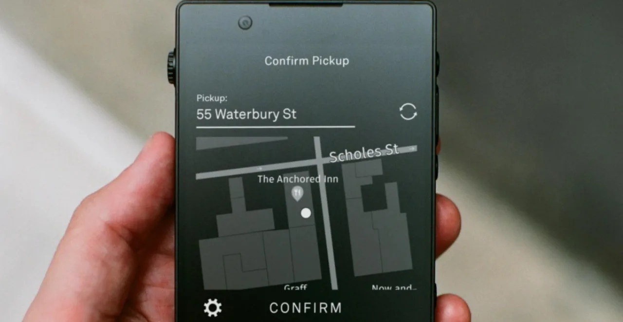 Light Phone com tela exibindo ícones da Uber e Lyft ao lado de um carro urbano ao fundo