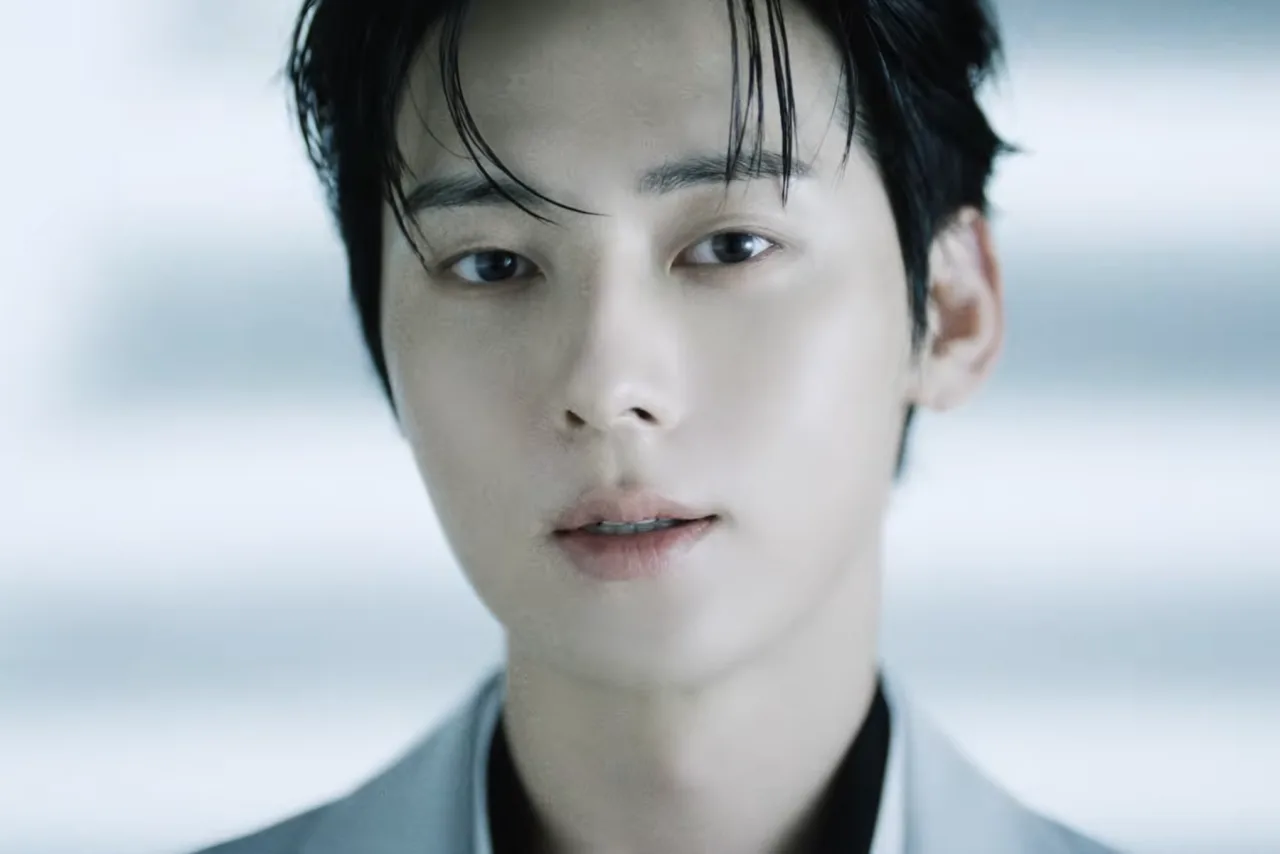 Hwang Minhyun aparece em fundo branco, vestindo camisa clara, segurando microfone ao lado do logo “OUR”
