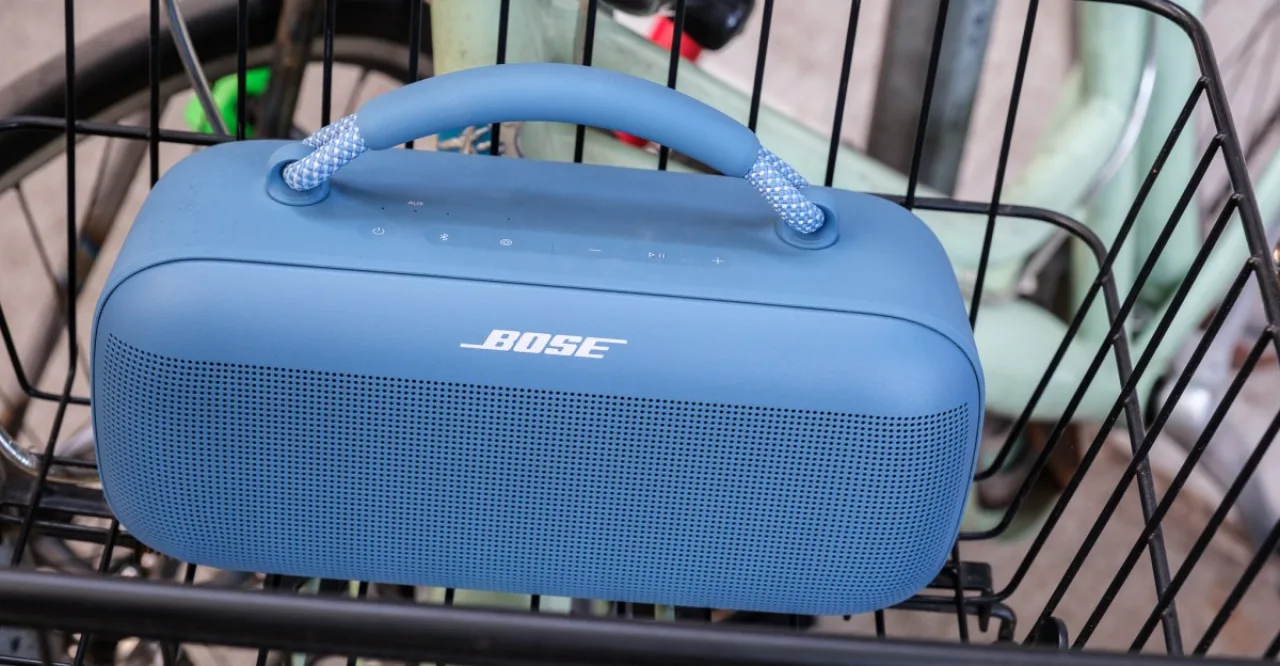 Pessoa correndo ao ar livre, usando fones, com o Bose SoundLink Max ao lado sobre uma esteira