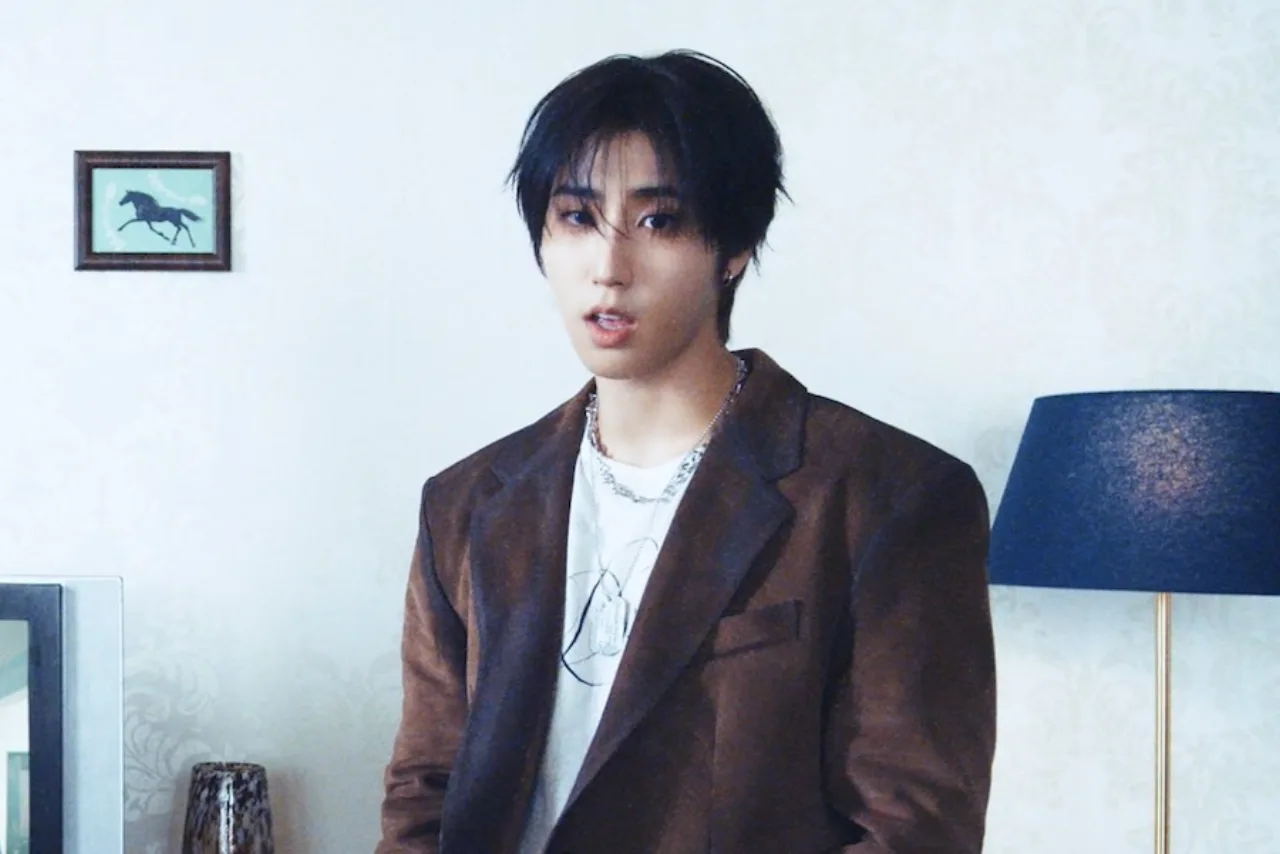 Han, do Stray Kids, aparece sorrindo ao lado de um bolo de aniversário e o logo da Angels Haven