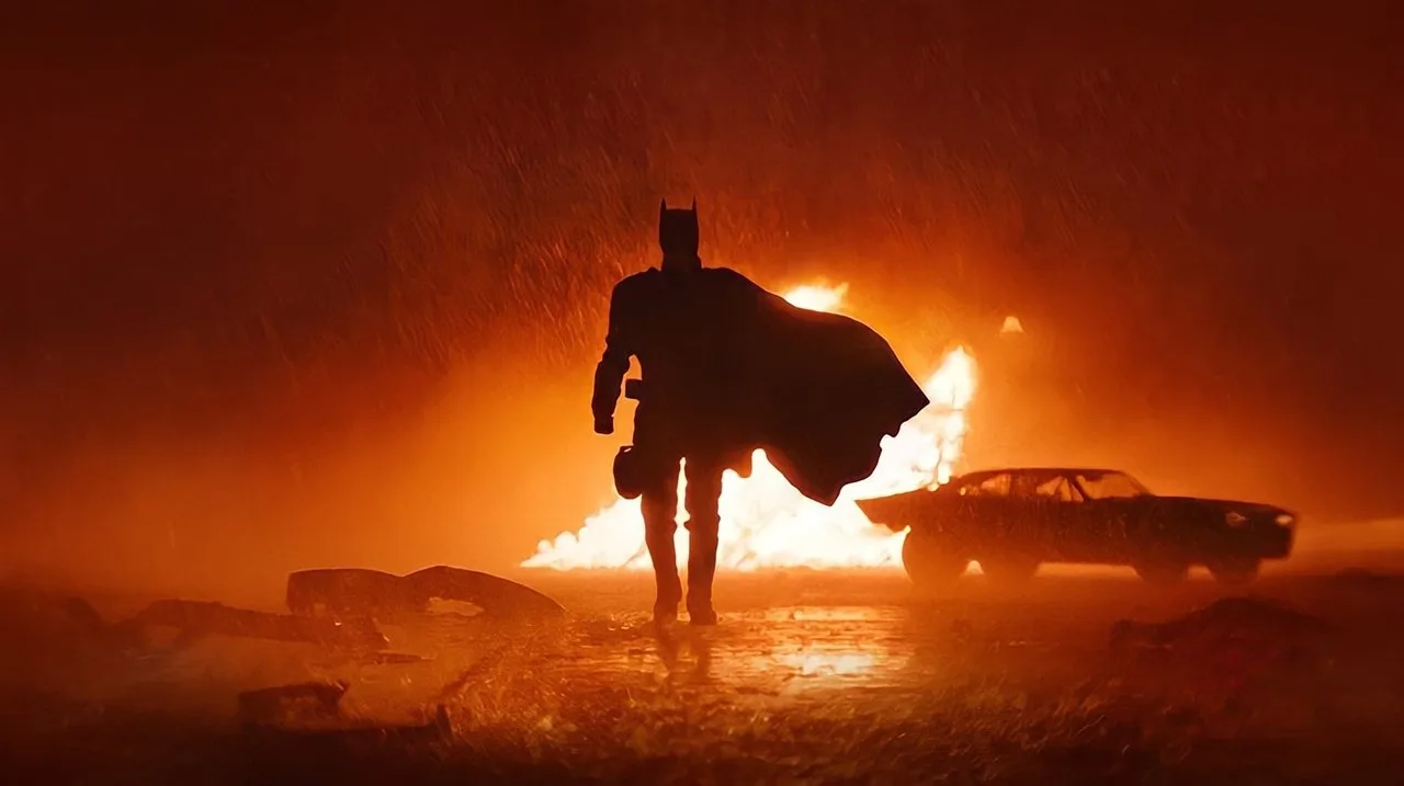 Um atleta musculoso vestindo capa e máscara do Batman, segurando halteres enquanto corre na esteira